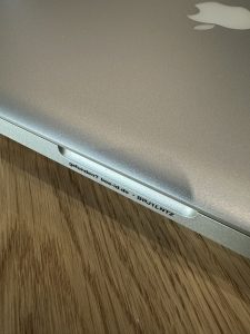 Nahaufnahme eines diskreten Fundservice Stickers am Griff eines silbernen Macbooks